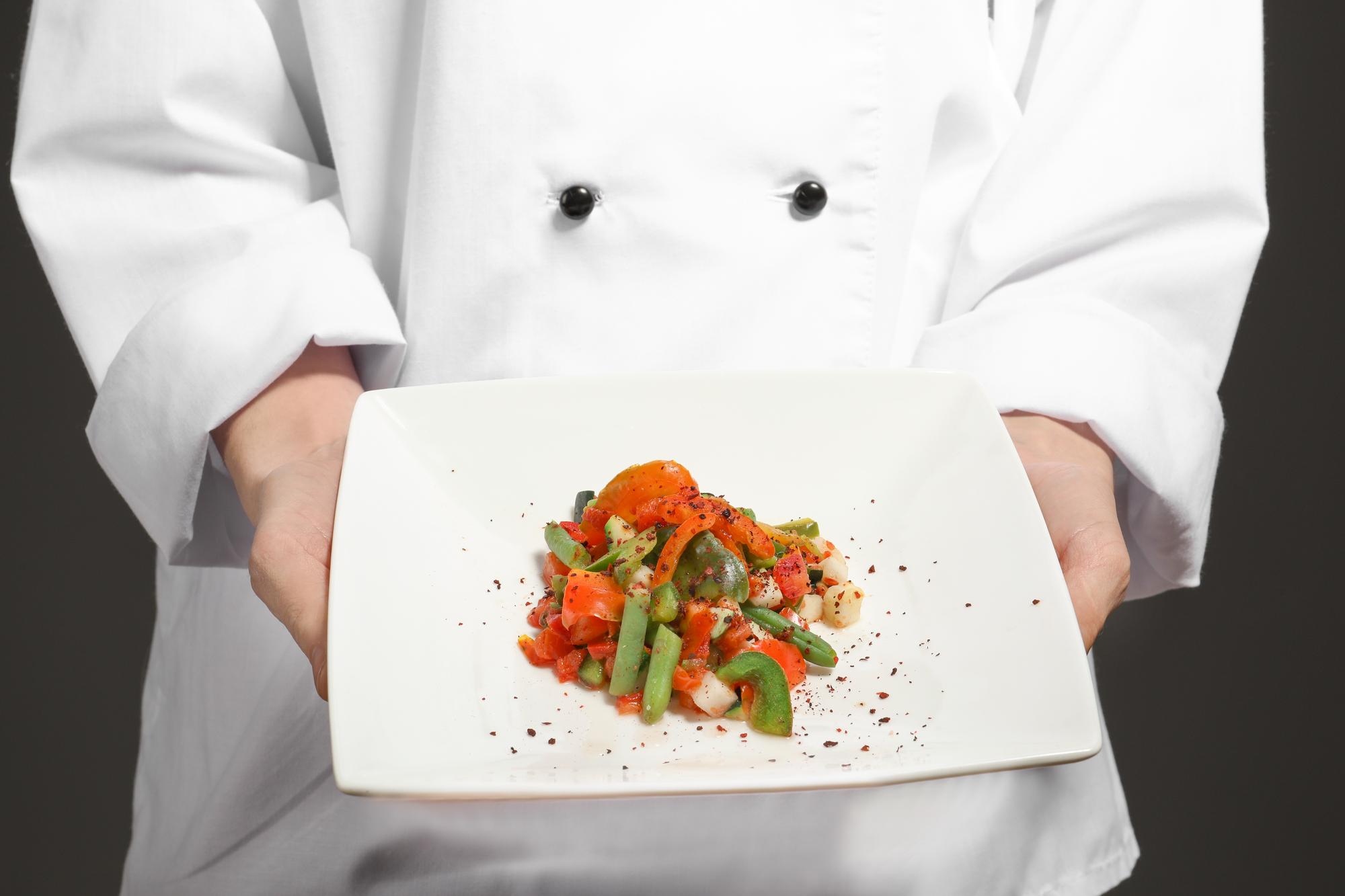 Chef prepara piatto gourmet in cucina elegante
